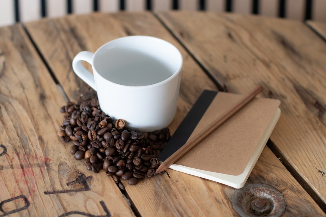 Open handwritten notebook with a cup of coffee on a wooden table